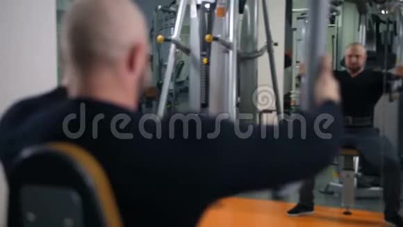 健身房里强壮的男人握手在镜子里反射4K慢莫视频的预览图