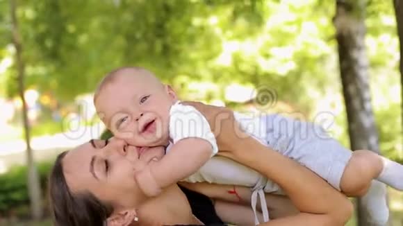 一位母亲在一个夏天的公园里拥抱她五个月大的儿子视频的预览图
