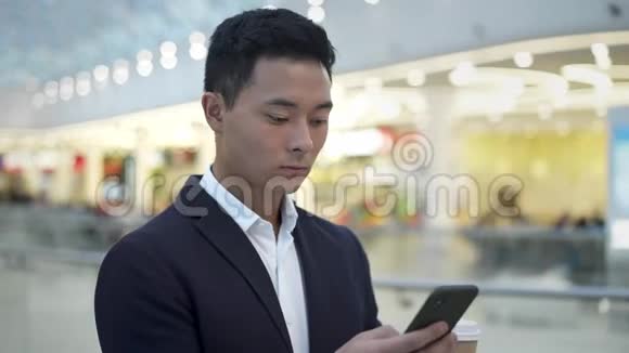 穿西装的亚洲年轻商人喝着咖啡打电话发短信视频的预览图