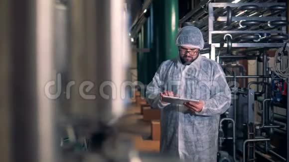 一个穿工作服的人正在酿酒厂对他的平板电脑进行计算视频的预览图