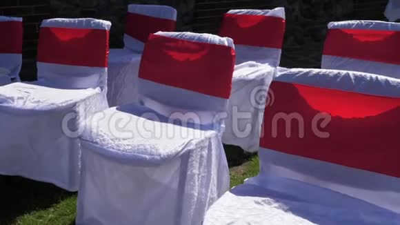 装饰着白色和红色布的椅子站在绿草的草坪上视频的预览图