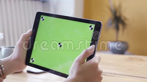 年轻的女人坐在桌子旁看着电脑平板电脑上面有彩色钥匙绿色屏幕库存数据视频的预览图
