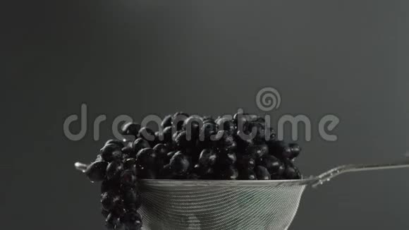 在视频中我们看到葡萄在筛子中水从顶部开始下降相机从上到下移动灰色背景视频的预览图