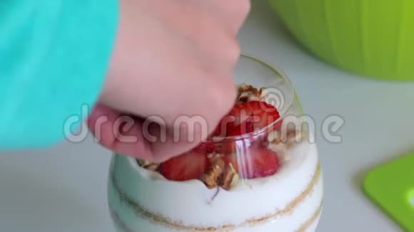一个女人在甜点里加了核桃玻璃层里铺着饼干碎屑和奶油从上面的点缀从草莓片视频的预览图