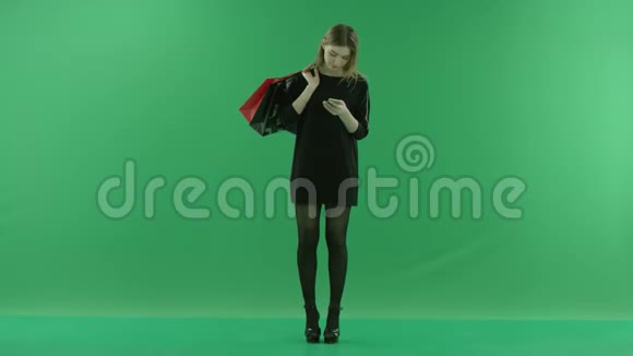 迷人的年轻女性在她的智能手机上键入短信肩后有购物袋颜色键绿色视频的预览图