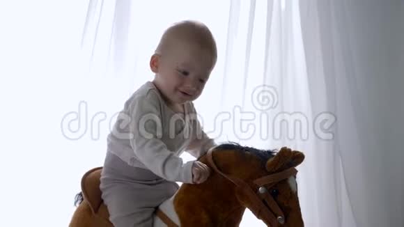 幼儿时期快乐的小男孩在家中骑着玩具马视频的预览图