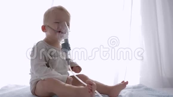 吸入程序可爱的幼儿男孩呼吸通过雾化器治疗气道炎症在明亮的房间视频的预览图