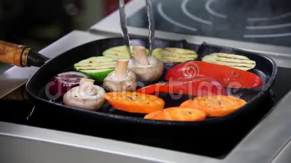 在厨房工作的厨师加热锅里的蘑菇和蔬菜把蘑菇翻过来视频的预览图