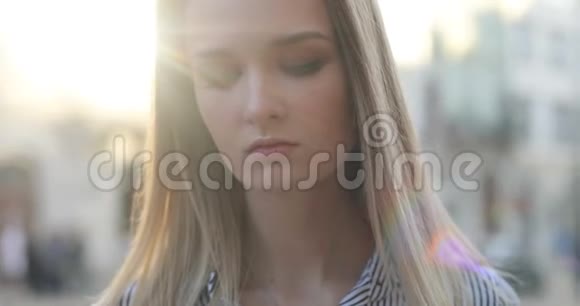 一个美丽的金发美女的特写肖像看着镜头街上有阳光视频的预览图