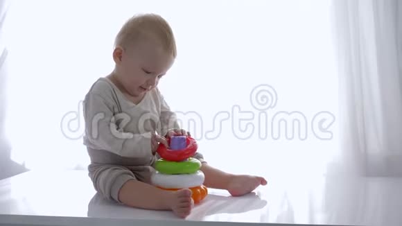 好奇的学步男孩在明亮的房间里玩教育玩具塔视频的预览图