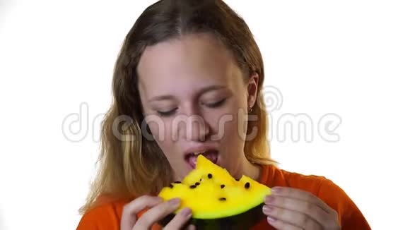 少女咬一片多汁的黄色西瓜在白色背景下视频的预览图