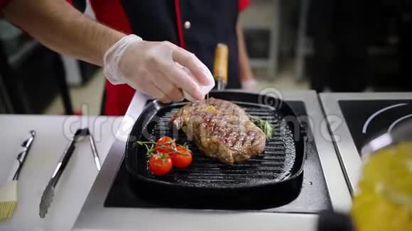 在厨房工作的厨师在锅里煎一块牛排然后把它刷过来视频的预览图