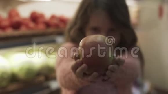 微笑的女孩手里拿着一个苹果放在架子上放着水果视频的预览图