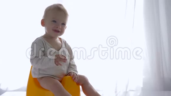 快乐健康的小男孩坐在马桶上在明亮的房间里把手指伸进嘴里视频的预览图