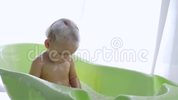 在明亮的房间里儿童看护快乐的孩子在浴缸里泼水视频的预览图