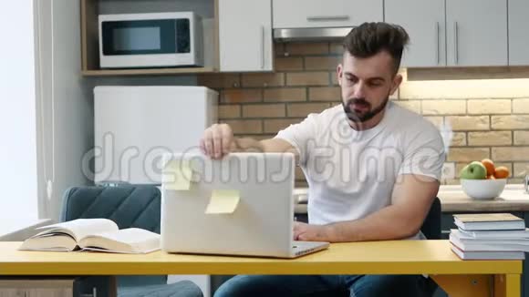 人类利用坐在家里厨房里的教科书在电脑上学习和写作业视频的预览图