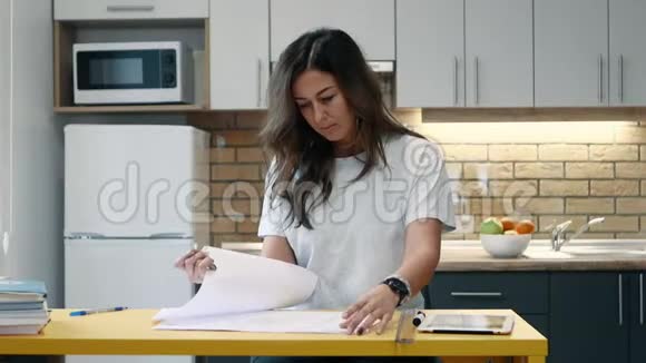 女建筑师在家里厨房里拿着文件工作视频的预览图