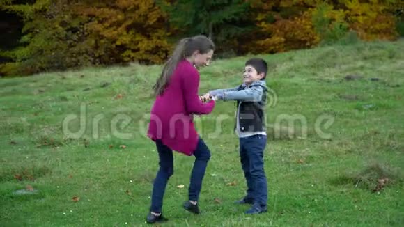 孩子们在秋天的森林里玩得很开心它们旋转着牵着手兄弟姐妹他们在笑视频的预览图