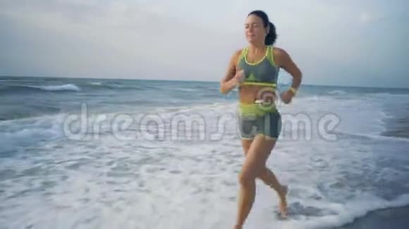 美丽的女孩在头上表演一个慢跑沿晨海海岸视频的预览图