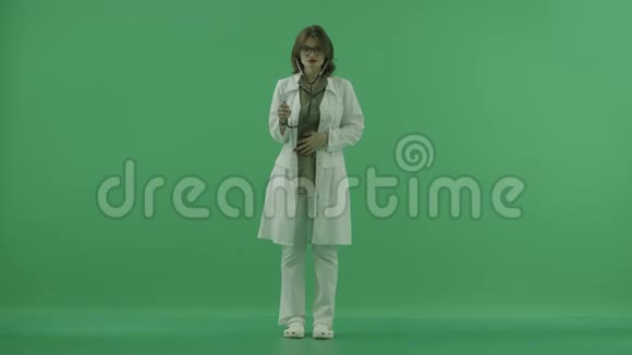 医生用听诊器听然后把它放在她的肩膀上的绿色屏幕上视频的预览图