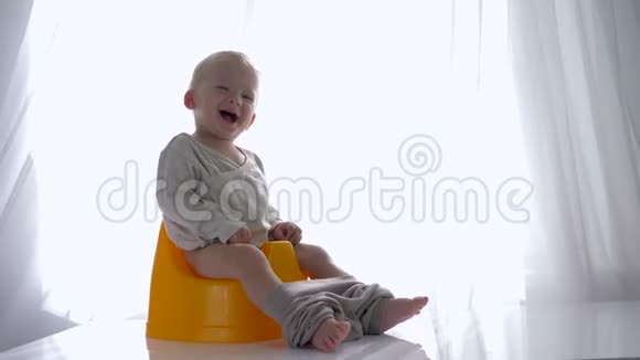 婴儿卫生笑得很好的婴儿坐在明亮的房间里的室内锅上视频的预览图