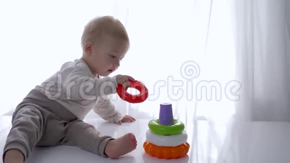 宝宝发育可爱的小男孩在明亮的房间里玩教育玩具金字塔视频的预览图