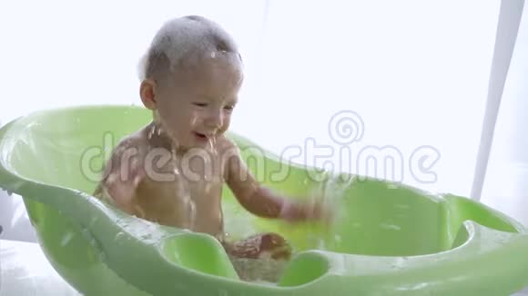 在明亮的房间洗澡时活跃的婴儿在洗澡时泼水视频的预览图