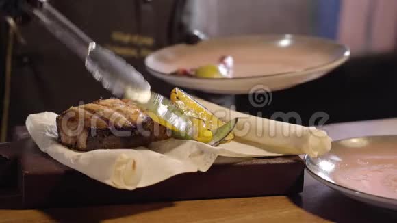 厨师把烤胡椒和柠檬片靠近一大块美味的三文鱼在皮塔使用钳子关闭准备视频的预览图
