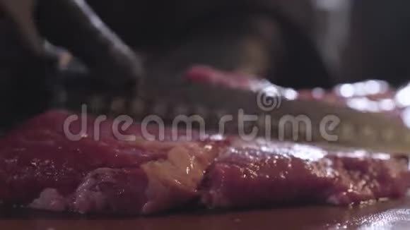 厨师手戴黑色厨师手套用大刀把生的多汁的肉切成小块准备食物视频的预览图