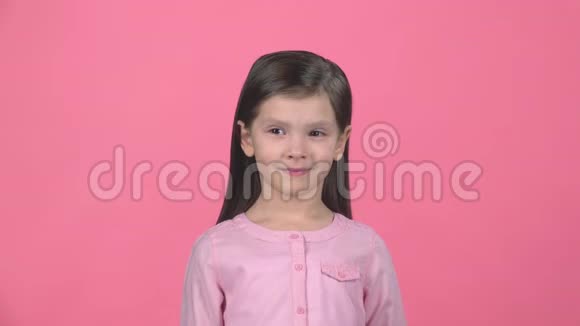 布鲁内特的孩子在粉红色的背景上微笑慢动作视频的预览图