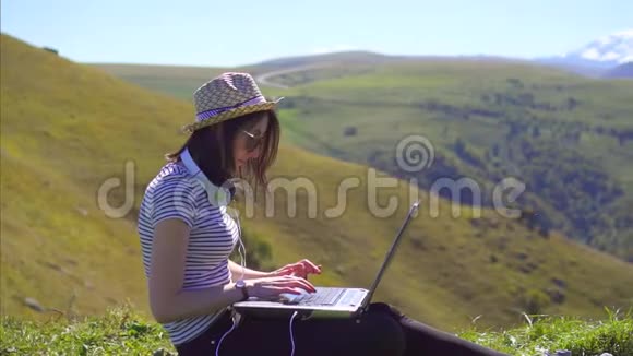 一个自由职业者女孩带着笔记本电脑在俯瞰群山的空地上的肖像慢悠悠视频的预览图