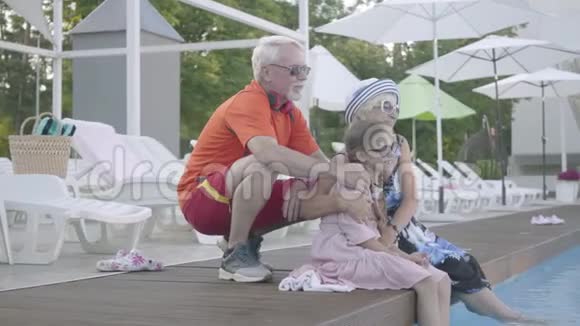 幸福成熟的情侣在池边搂着小孙女奶奶爷爷和孙子在挥手视频的预览图