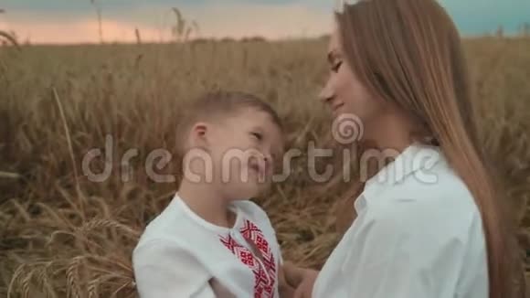 年轻的母亲和孩子儿子躺在麦田里拥抱着一起玩美丽的女人和小可爱的男孩在一起视频的预览图