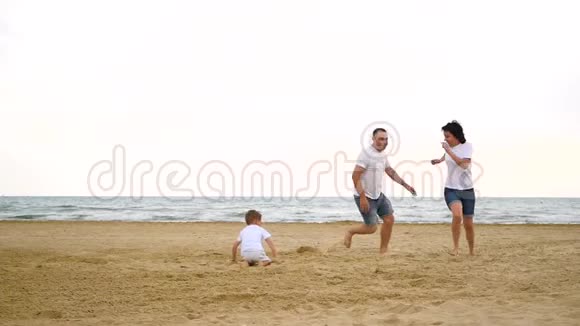 一个幸福的家庭三个人在沙滩上互相跑来跑去动作缓慢视频的预览图