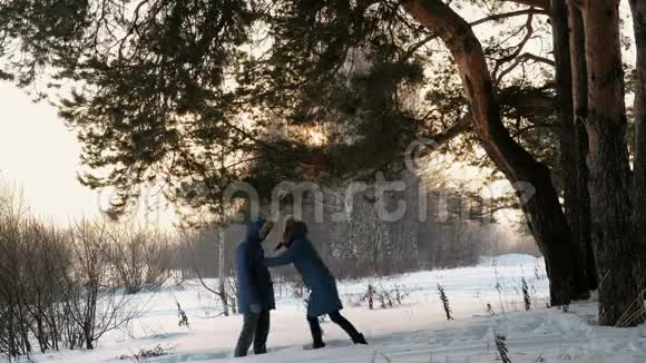 女人把男人推入雪岸两人都穿着蓝色夹克视频的预览图