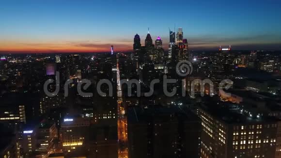 令人叹为观止的4k无人驾驶飞机空中全景在橙色日落黄昏的天空中夜光大城市费城城市景观视频的预览图