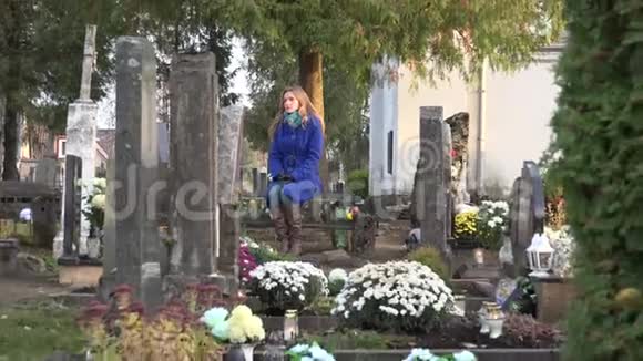 悲伤的女人坐在墓地丈夫父亲坟墓附近的长凳上放大4K视频的预览图