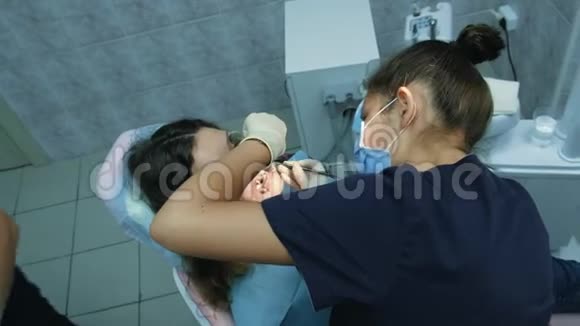 去看牙医正畸医生为一名带牙固位的妇女设置铁支架俯视图视频的预览图