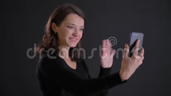 年轻迷人的白种人长发女孩用黑色智能手机在电视上微笑交谈的肖像视频的预览图