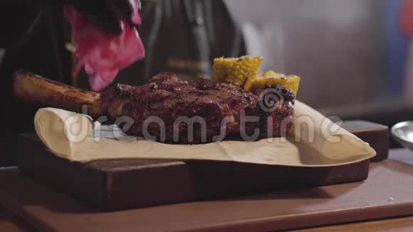 厨师手戴黑色厨师手套把红白菜和蘑菇和胡萝卜放在烤肉附近视频的预览图