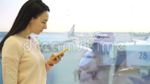 国际机场智能手机年轻女性肖像在机场休息室等候的航空乘客视频的预览图