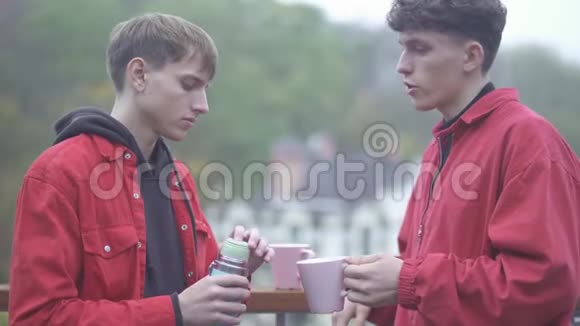 年轻人把茶杯里的热水瓶里的茶倒给朋友朋友朋友一起出去玩视频的预览图