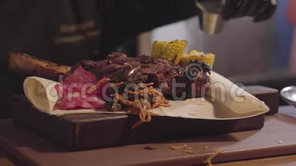 厨师戴着黑色炊具手套端在盘子里烤肉烤玉米切片酱汁和生姜关门视频的预览图