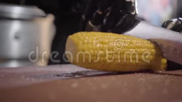 厨师在黑色炊具手套切割和切片果汁甜玉米烤在木桌上关门视频的预览图