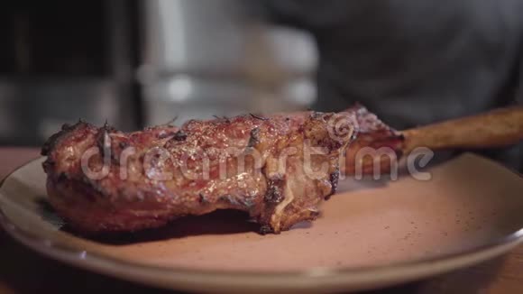 在餐厅的厨房桌子上一个盘子上骨头上的烤肉美味多汁的肉片特写视频的预览图