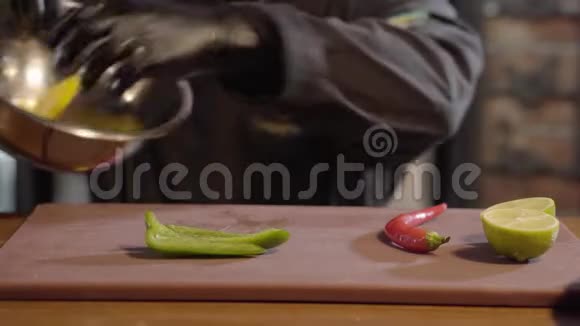 厨师的手把青椒和红椒与切好的柠檬放在大铝碗里穿黑色长袍和橡胶的男人视频的预览图