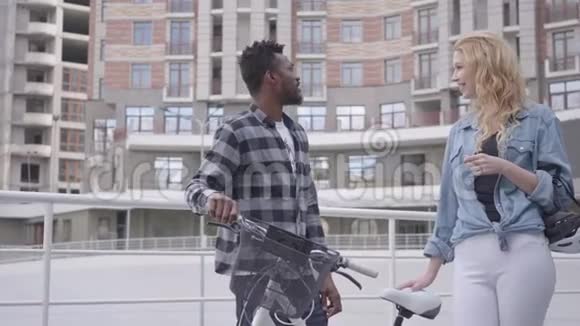 在城市建筑背景下英俊的非裔美国人站在自行车的背景下与人交谈视频的预览图