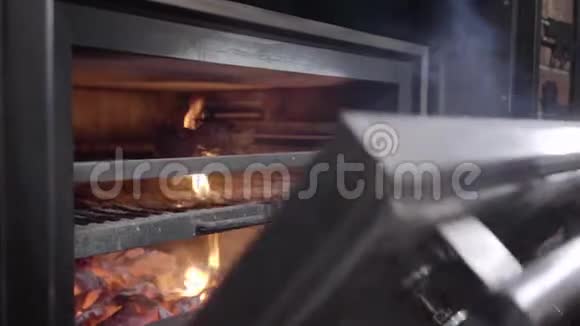 在黑色橡胶手套中烹饪打开烤炉用金属工具近距离拉出一块带火的肉这就是视频的预览图