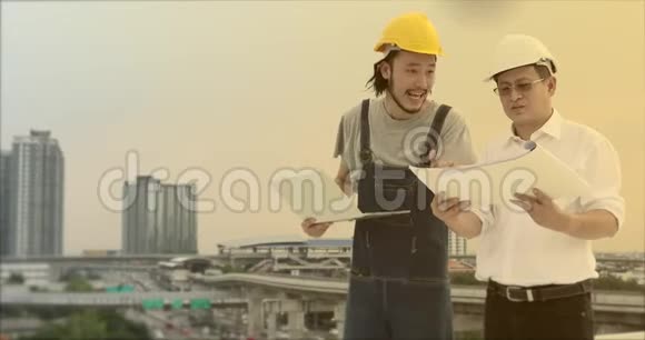 亚洲工程师站在屋顶上年轻人用笔记本向老人解释他的工作视频的预览图