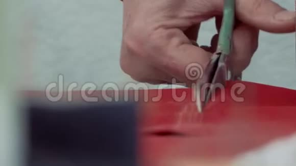 女的手剪剪刀把剪刀红色的布料剪在画线上视频的预览图